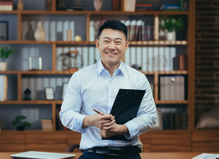 A smiling director of a limited company holding a clipboard and pen
