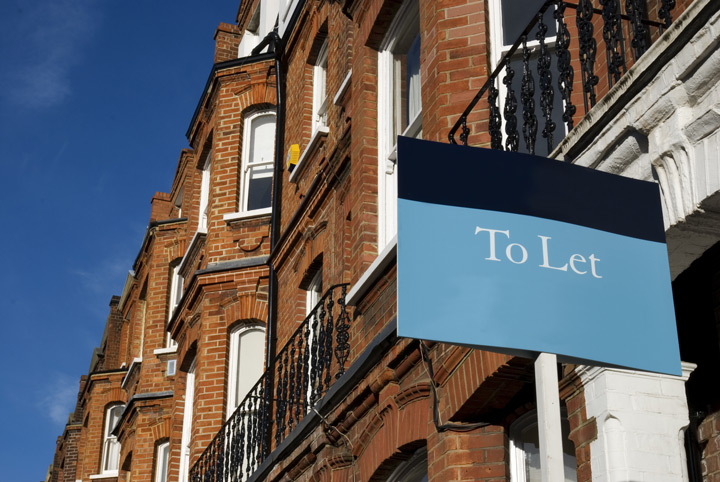 low angle shot of brown brick terrace houses with a To Let sign in foreground