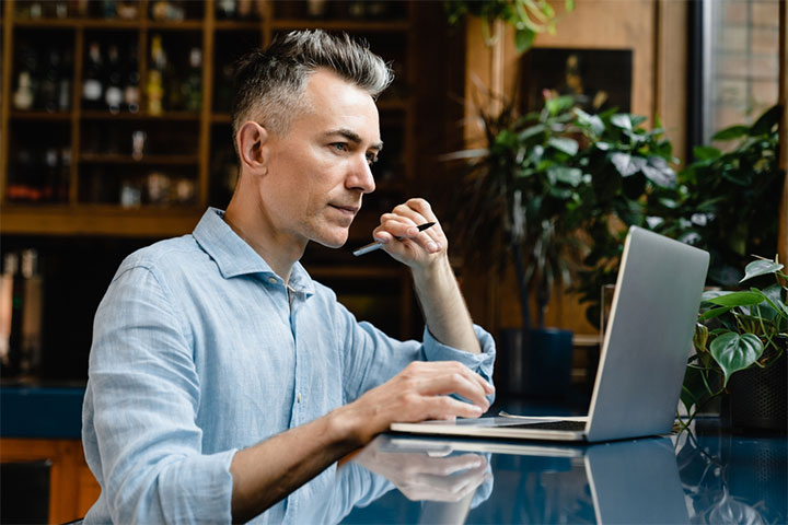A person sitting at a table with a computer, starting up their first business as a contractor/ freelancer